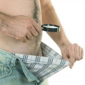 un bărbat își privește în jos pantalonii și vrea să-și mărească penisul cu gel